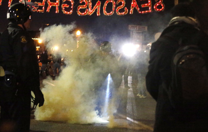 A police officer is engulfed in smoke from a device thrown into the police line by protesters in Ferguson, Missouri, November 25, 2014. (Reuters/Jim Young)