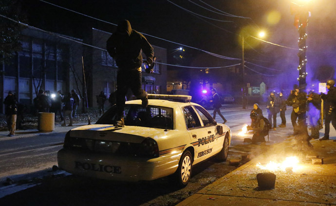 A protester jumps on a Ferguson police car set on fire by protesters in Ferguson, Missouri, November 25, 2014. (Reuters/Jim Young)