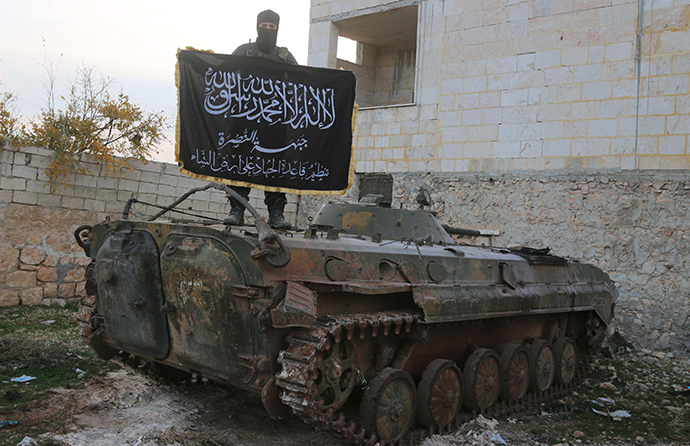 A member of al Qaeda's Nusra Front poses with the Nusra flag on top of an infantry fighting vehicle at the frontline near al-Zahra village, north of Aleppo city, November 25, 2014 (Reuters / Abdalrhman Ismail)