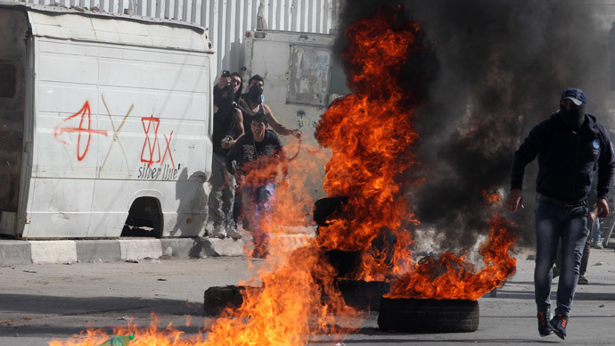Palestinian protestors stand near burning tyres during clashes with Israeli security forces in the West Bank city of Hebron following a demonstration in support of Palestinians entering the Al-Aqsa mosque compound in Jerusalem for Friday prayers on November 14, 2014.(AFP Photo / Hazem Bader)
