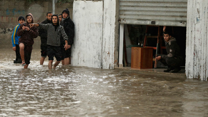 A man looks out of his shop as Palestinians walk through a flooded road following heavy rain in Gaza City November 27, 2014.(Reuters / Mohammed Salem)