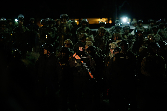 A demonstrator protesting the shooting death of Michael Brown shines a spot light on a group of police officers and National Guard troops outside of the Ferguson Police Station November 28, 2014 in Ferguson, Missouri (AFP Photo / Joshua Lott)
