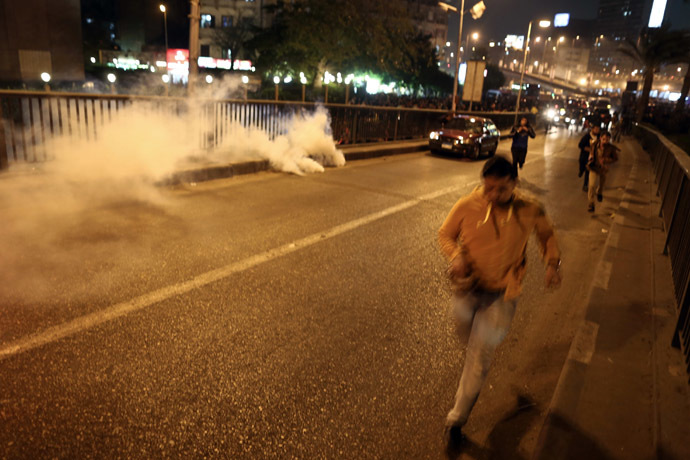 Egyptian anti-Mubarak protesters run for cover from smoke-grenades fired by the police during clashes in Tahrir Square in Cairo on November 29, 2014. (AFP Photo)