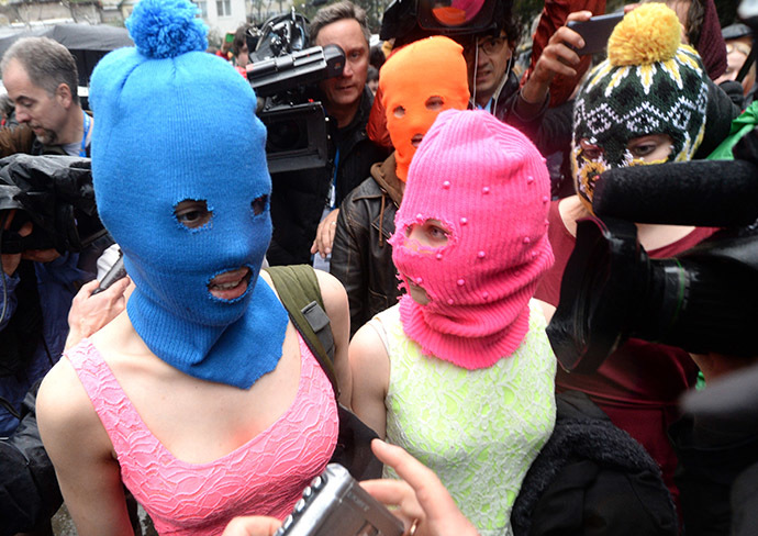 Wearing masks are members of Russian punk group Pussy Riot, Nadezhda Tolokonnikova (L) and Maria Alyokhina (R). (AFP Photo/Andrej Isakovic)