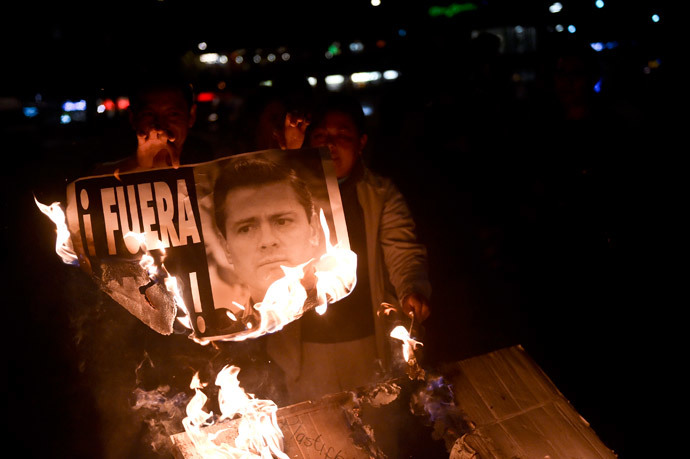 Demonstrators burn a banner bearing the image of Mexican President Enrique Pena Nieto along Reforma Avenue during a protest demanding justice in the case of the 43 missing students from Ayotzinapa, on December 1, 2014 in Mexico City. (AFP Photo / Yuri Cortez)