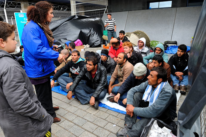 An interpreter from Caritas France speaks with Syrian refugees at the Calais port, a departure point for ships bound for Britain (AFP Photo)