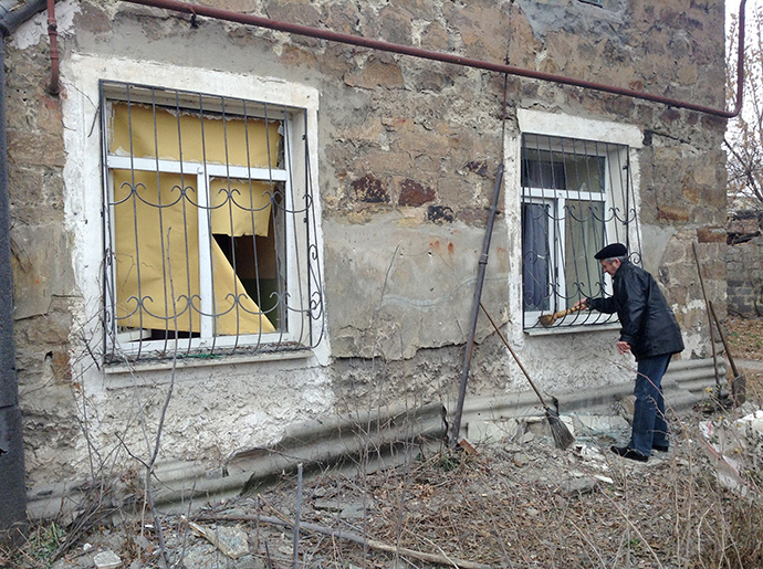 A residents of Azotny district clears the area around his house following shelling which killed a 12-year-old boy and a 55-year-old woman, Donetsk, Ukraine (RIA Novosti)