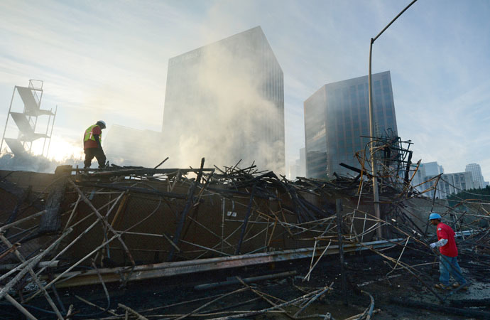 Workers survey damage after a huge fire in downtown Los Angeles, California, December 8, 2014. (AFP Photo/Robyn Beck)