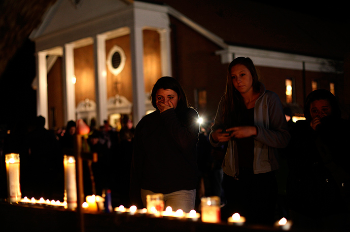 ARCHIVE PHOTO: A woman covers her mouth as others look on stand near candles outside Saint Rose of Lima Roman Catholic Church near Sandy Hook Elementary School, where a gunman opened fire on school children and staff in Newtown, Connecticut December 14, 2012 (Reuters / Joshua Lott)