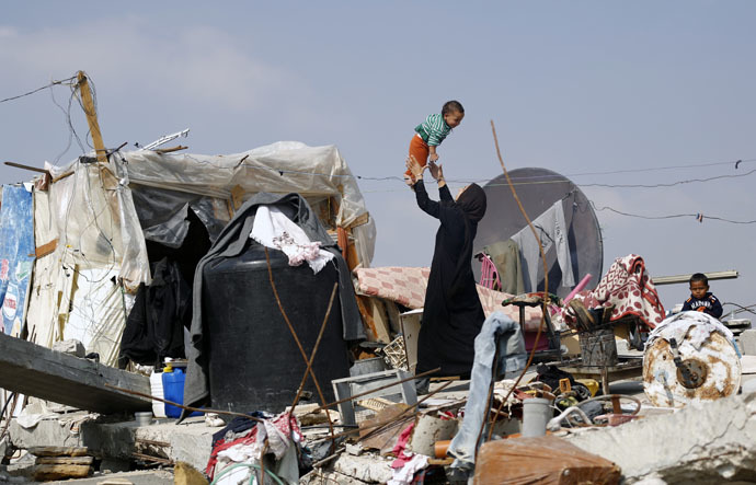 A Palestinian woman plays with her child on the rubble of their family's home which was destroyed during the 50-day Gaza war between Israel and Hamas-led militants in the Gaza Strip, on November 12, 2014, in Khan Yunis' Khuzaa neighbourhood in the southern Gaza Strip near the Israeli border. (AFP Photo)