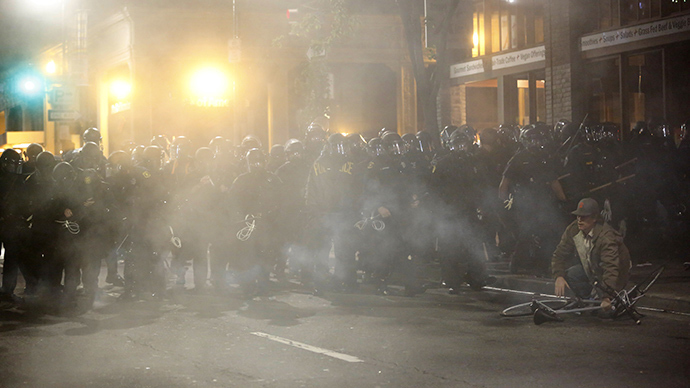 A demonstrator throws backs a teargas canister toward the police line during the fourth night of demonstrations over recent grand jury decisions in police-involved deaths on December 6, 2014 in Berkeley, California (AFP Photo / Stephen Lam)