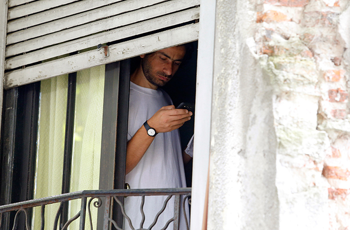 Former Guantanamo detainee Ahmed Adnan Ahjam from Syria uses a mobile phone while standing near a window in a neighbourhood in Montevideo December 12, 2014 (Reuters / Andres Stapff)