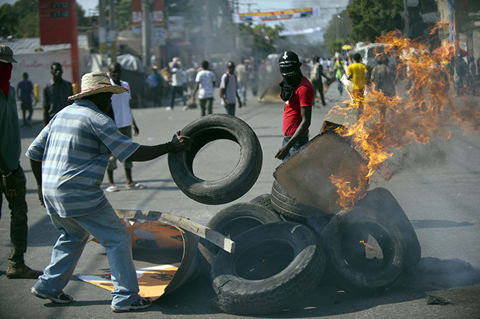 Protesters block a street with burning tires and barricades in the center of Port-au-Prince, on December 13, 2014. (AFP Photo/Hector Retamal)