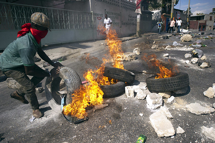 Protesters block a street with burning tires and barricades in the center of Port-au-Prince, on December 13, 2014. (AFP Photo/Hector Retamal)