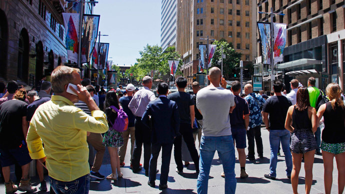 People standing behind a police cordon look towards Lindt cafe in Martin Place, where hostages are being held, in central Sydney December 15, 2014.(Reuters / David Gray)
