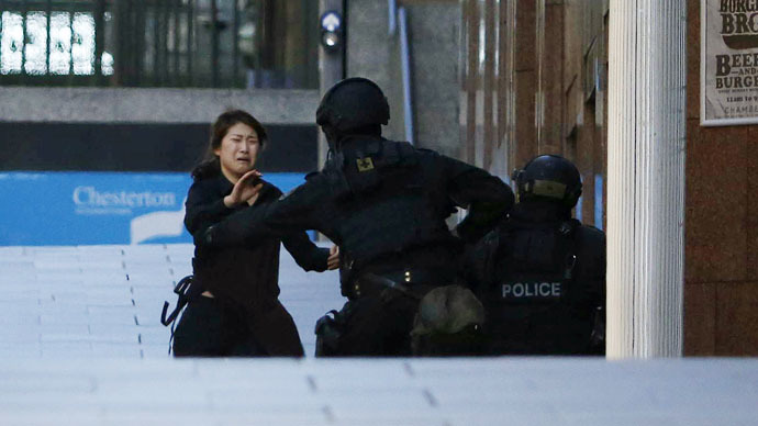 A hostage runs towards a police officer outside Lindt cafe, where other hostages are being held, in Martin Place in central Sydney December 15, 2014. (Reuters/Jason Reed)