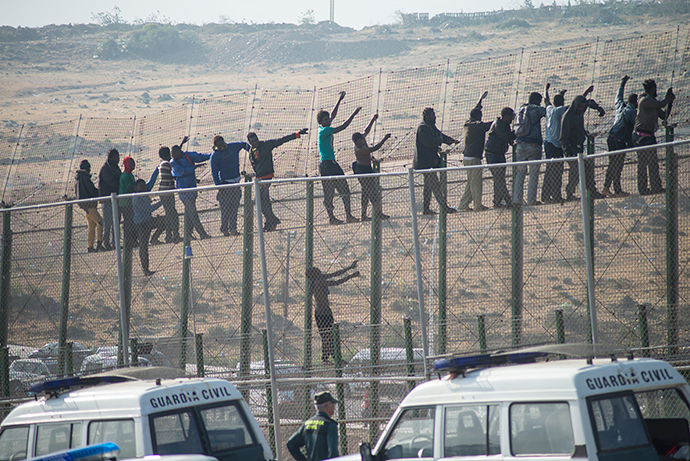 Would-be immigrants stand atop a boarder fence separating Morocco from the north African Spanish enclave of Melilla on May 1, 2014, following a morning assault on the boarder in an attempt to cross into Spain.( AFP Photo / Blasco De Aellaneda)