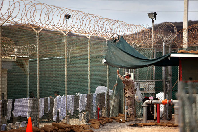 In this photo, reviewed by the US Military, a guard leans on a fence talking to a Guantanamo detainee, inside the open yard at Camp 4 detention center, at the US Naval Base, in Guantanamo Bay, Cuba, January 21, 2009. (AFP Photo)