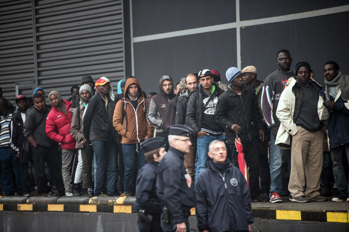 French CRS officers stand by to survey as humanitarian organizations distribute food to migrants in the northeastern French port of Calais on October 29, 2014. (AFP Photo)