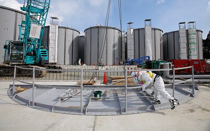 Men wearing protective suits and masks work in front of welding storage tanks for radioactive water, under construction in the J1 area at the Tokyo Electric Power Co's (TEPCO) tsunami-crippled Fukushima Daiichi nuclear power plant in Okuma in Fukushima prefecture (AFP Photo / Toru Hanai / Pool)