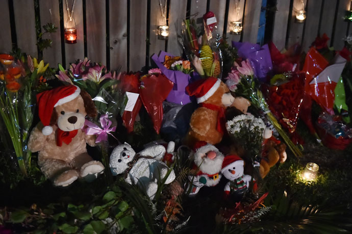 Flowers and stuffed toys are laid opposite the scene where eight children ranging from babies to teenagers were found dead in a house in the northern Australian city of Cairns early on December 20, 2014. (AFP Photo)