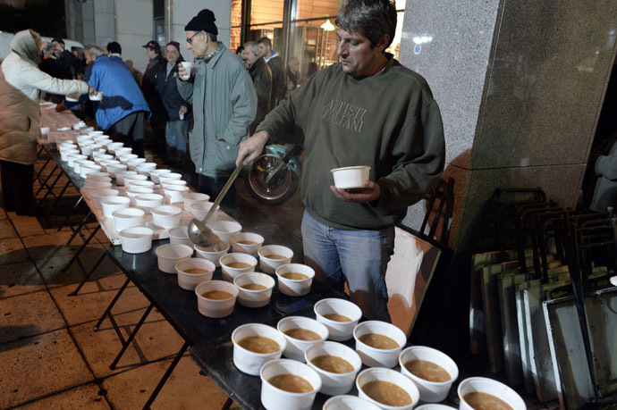 A Volunteer serves a hot bean soup outside the finance ministry in Athens. (AFP Photo/Louisa Gouliamaki)