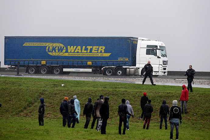 French police prevent a group of migrants from jumping onto lorries on their way to the ferry terminal in Calais (Reuters / Pascal Rossignol)