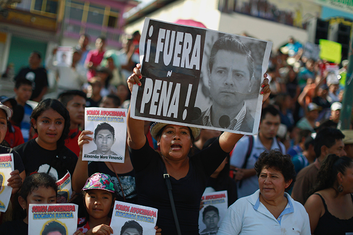 A woman holds a sign during a protest demanding justice for the 43 missing students of the Ayotzinapa Teacher Training College Raul Isidro Burgos, in Tecoanapa, in the southern Mexican state of Guerrero, December 11, 2014. (Reuters / Jorge Dan Lopez)