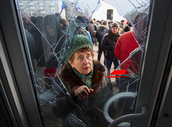 A woman looks through a damaged entrance door as pro-Russian demonstrators hold a rally outside the regional government building in Donetsk, March 3, 2014. (Reuters / Stringer)