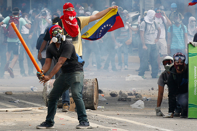 Anti-government demonstrators pretend to bat gas canisters to police during riots in Caracas April 1, 2014. (Reuters / Christian Veron)