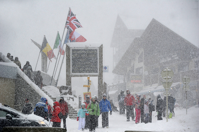 People walk at the Les Saisies ski resort in Savoie, central-eastern France, as snow falls on December 27, 2014. (AFP Photo / Jean-Pierre Clatot) 