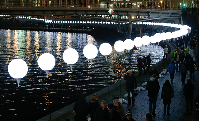 People walk under the lit balloons installation along the river Spree in Berlin November 8, 2014. (Reuters / Fabrizio Bensch)