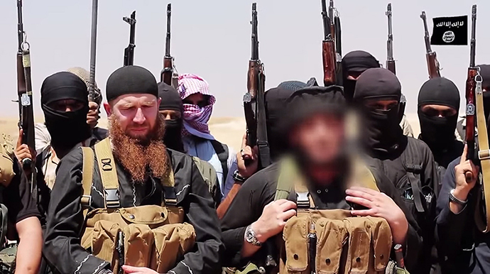 Members of the IS (Islamic state) including military leader and Georgian native, Abu Omar al-Shishani (Tarkhan Batirashvili) (C-L) and ISIL sheikh Abu Mohammed al-Adnani (C-R), whose picture was blurred from the source to protect his identity, speaking at an unknown location between the Iraqi Nineveh province and the Syrian town of Al-Hasakah on June 29, 2014. (AFP Photo / HO / Al-Itisam Media)