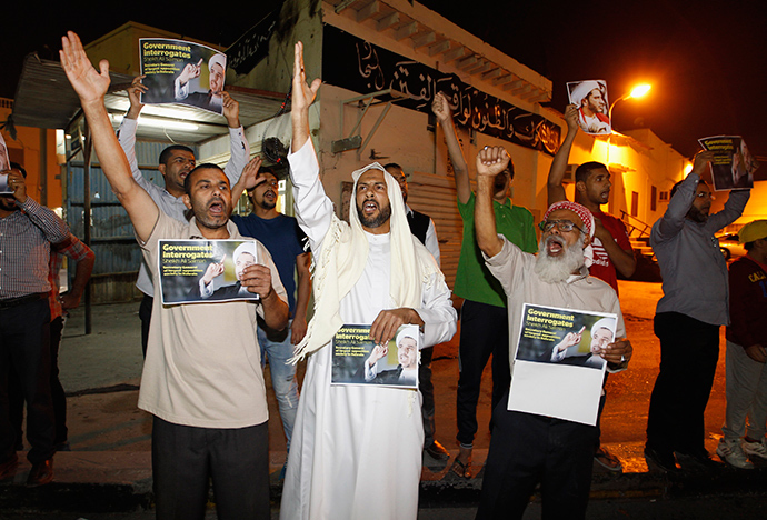 Protesters, holding placards with an image of Al Wefaq Secretary-General Sheikh Ali Salman, shout anti-government slogans as they gather outside Salman's home, in the village of Bilad Al Qadeem, south of Manama, December 28, 2014 (Reuters / Hamad I Mohammed)