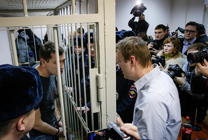 Russian opposition leader and anti-corruption blogger Alexey Navalny (R) talks with his brother and co-defendant Oleg (inside defendants cage) during a court hearing in Moscow December 30, 2014 (Reuters / Sergey Karpukhin)