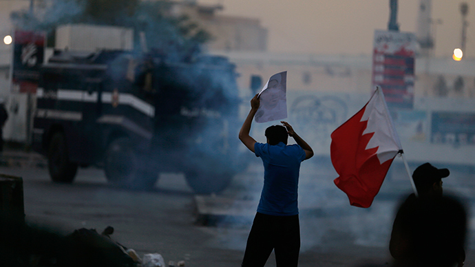 A protester holds an image of Al Wefaq Secretary-General Sheikh Ali Salman as he confronts a riot police armoured personal carrier during clashes between police and demonstrators protesting for Salman, in the village of Bilad Al Qadeem, south of Manama, December 29, 2014 (Reuters / Hamad I Mohammed)