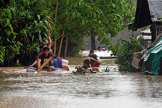 Residents help each other out from their inundated neighborhoods after rains spawned by a tropical storm, locally known as Seniang, caused flooding in Misamis Oriental on the southern Philippine island of Mindanao on December 29, 2014 (AFP Photo / Erwin Mascarinas)