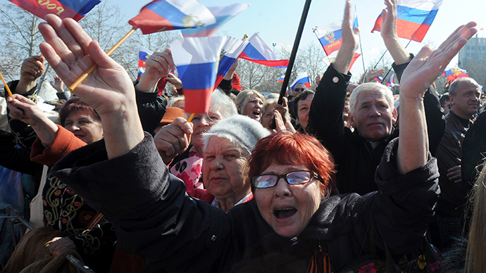 People react as they watch the Russian President make a speech on a huge screen set in the center of the city of Sevastopol, in Crimea, on March 18, 2014. (AFP Photo / Viktor Drachev)