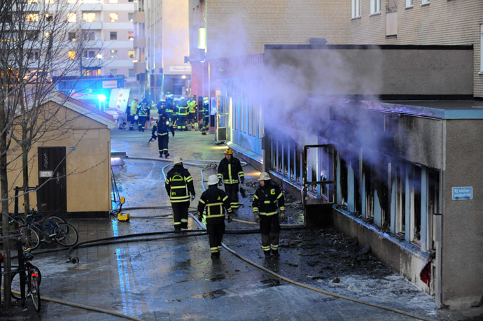 Smoke rises from the interior of a destroyed cellar mosque as firefighters walk in front of the building after an arson attack on December 25, 2014 in Eskilstuna, central Sweden. (AFP/TT News Agency)