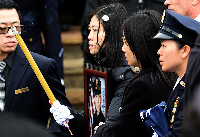 Pei Xia Chen (C), widow of New York Police Department (NYPD) officer Wenjian Liu, walks holding a picture of her husband during his funeral in New York's borough of Brooklyn on January 4, 2015. (AFP Photo/Jewel Samad)