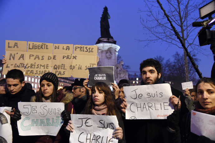 A man holds a placard reading : "Freedom of the press is priceless, fundamentalism, of any kind, will not pass" as others hold up placards reading in French, "I am Charlie" during a gathering at the Place de la Republique (Republic square) in Paris, on January 7, 2015 (AFP Photo / Dominique Faget)