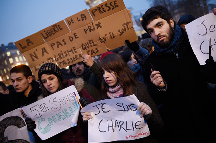 A man holds a placard reading : "Freedom of the press is priceless, fundamentalism, of any kind, will not pass" as others hold up pens and placards reading in French, "I am Charlie" during a gathering at the Place de la Republique, following an attack by unknown gunmen on the offices of the satirical weekly, Charlie Hebdo (AFP Photo / Martin Bureau)