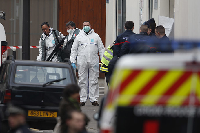 Firefighters and police investigators stand in front of the entrance of the Paris offices of Charlie Hebdo January 7, 2015 after a shooting. (Reuters/Charles Platiau)