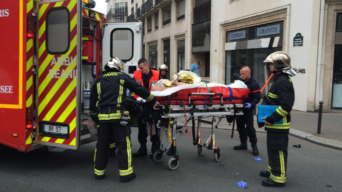 Firefighters carry an injured man on a stretcher in front of the offices of the French satirical newspaper Charlie Hebdo in Paris on January 7, 2015.(AFP Photo / Philippe Dupeyrat)