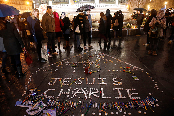 People gather near candles with the message, "I am Charlie" as they continue to pay tribute to the shooting victims on Wednesday at the satirical weekly Charlie Hebdo, at the Republique square in Paris January 10, 2015 (Reuters / Pascal Rossignol)