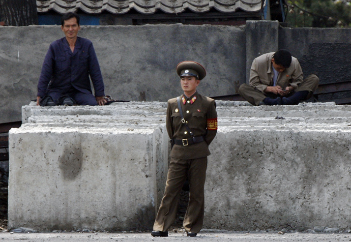 A North Korean worker checks his mobile phone as a soldier stands in front along the banks of Yalu River, near the North Korean town of Sinuiju, opposite the Chinese border city of Dandong (Reuters / Jacky Chen)