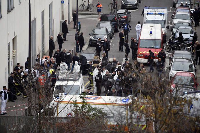 Firefighters, police officers and forensics gathered in front of the offices of the French satirical newspaper Charlie Hebdo after armed gunmen stormed the building leaving twelve dead. (AFP Photo)