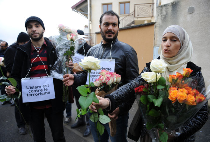 Muslims with placards reading "Islam is against terrorism" offer roses in the Sablons neighborhood of Le Mans, western France, on January 10, 2015, in front of the mosque against which bullets were fired and 3 grenades launched on January 8. (AFP Photo)