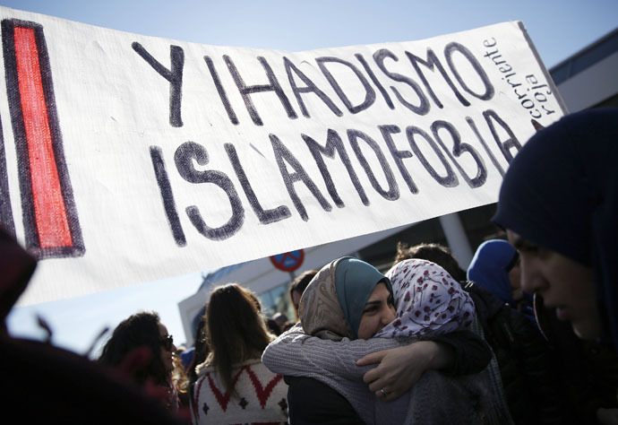 Two women embrace under a banner that reads, "No to Islamophobia and jihadism" during a rally outside Madrid's Atocha train station on January 11, 2015. (Reuters)