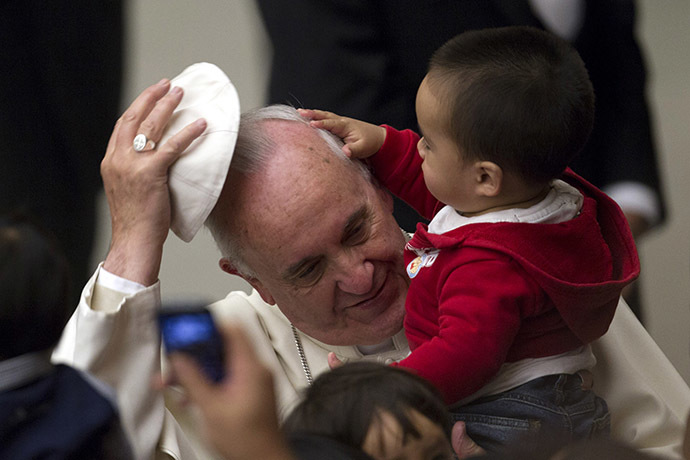 Pope Francis has his skull cap removed by a child during an audience with children assisted by volunteers of Santa Marta institute in Paul VI hall at the Vatican December 14, 2013. (Reuters/Giampiero Sposito)